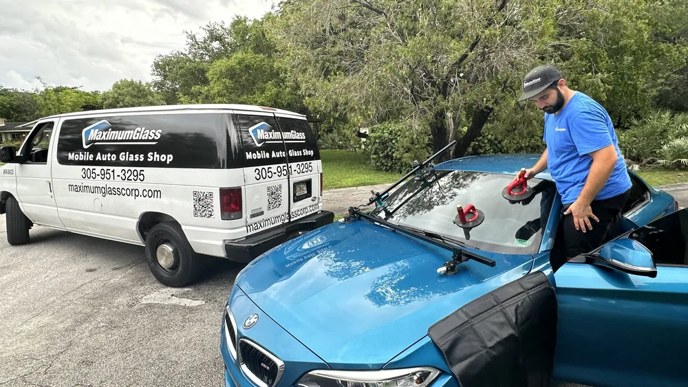 Technician cleaning the new windshield beside the branded Maximum Glass van
